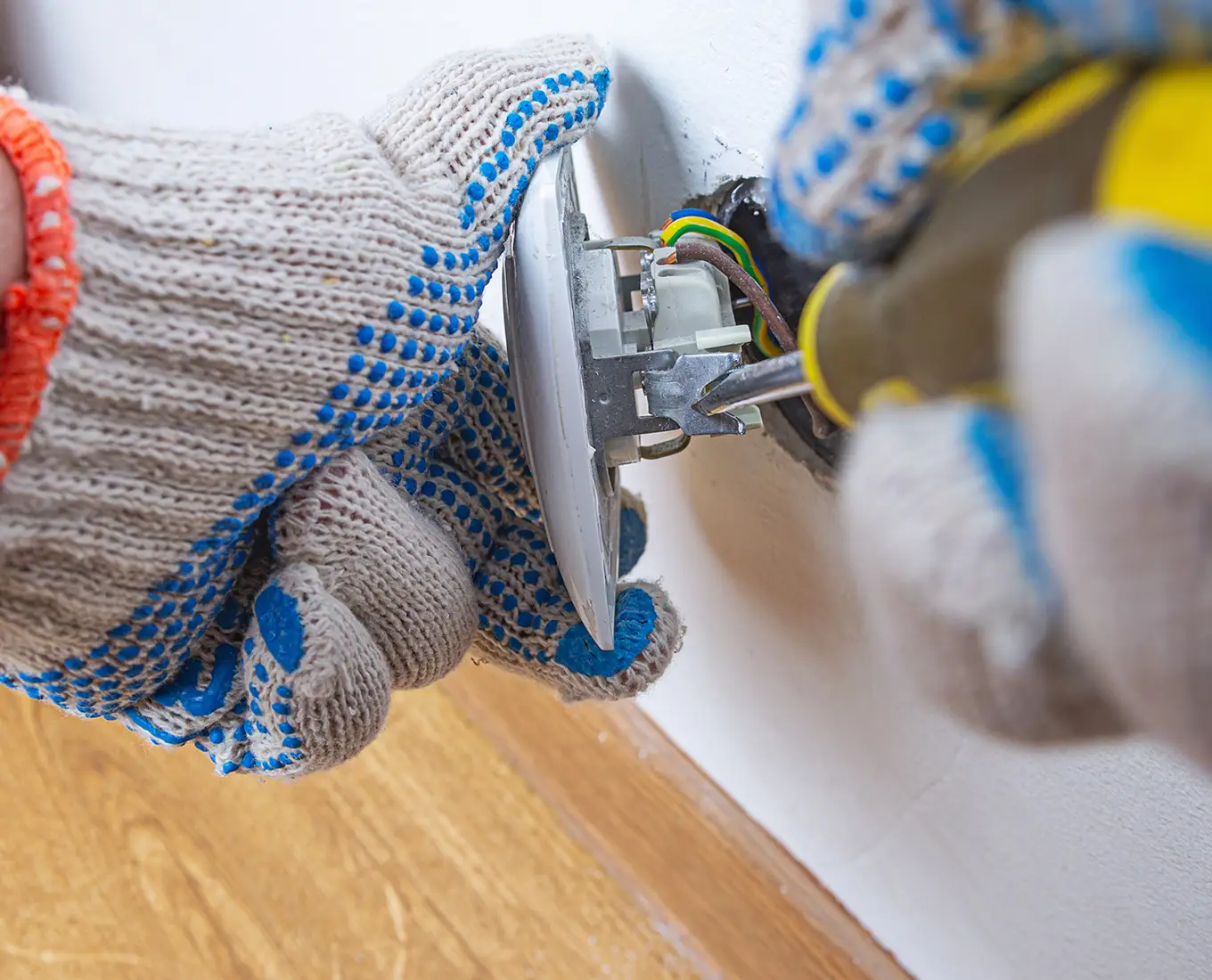 Electrician repairing a wall outlet in a Belleville, IL home, showcasing professional electrical services.
