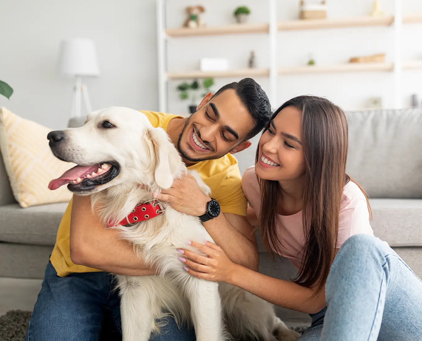 young couple with their Golden Retriever sit comfortable on their living room floor